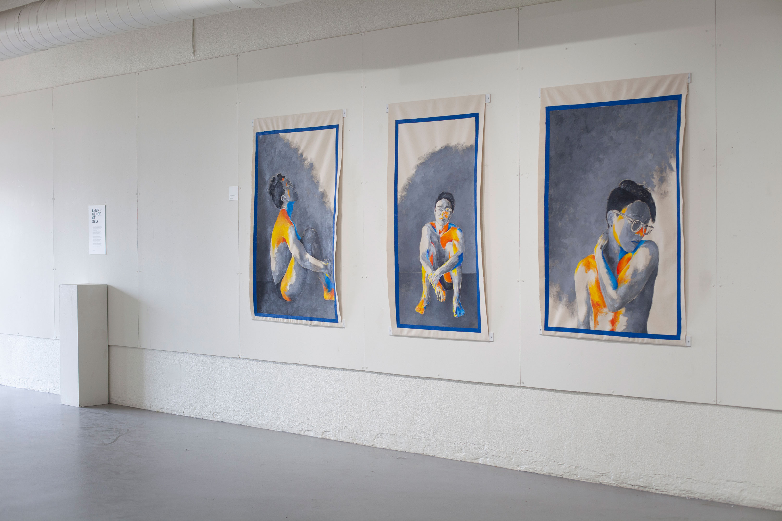 three large canvas paintings about 6 feet tall, pinned onto a spacious wall